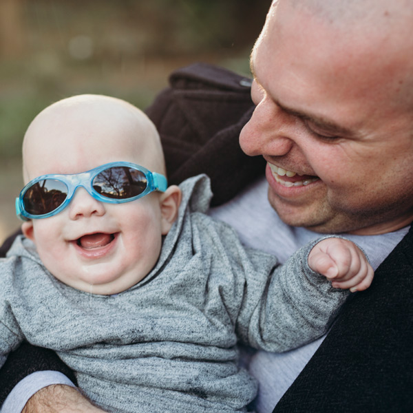 Baby in sunglasses held by Dad